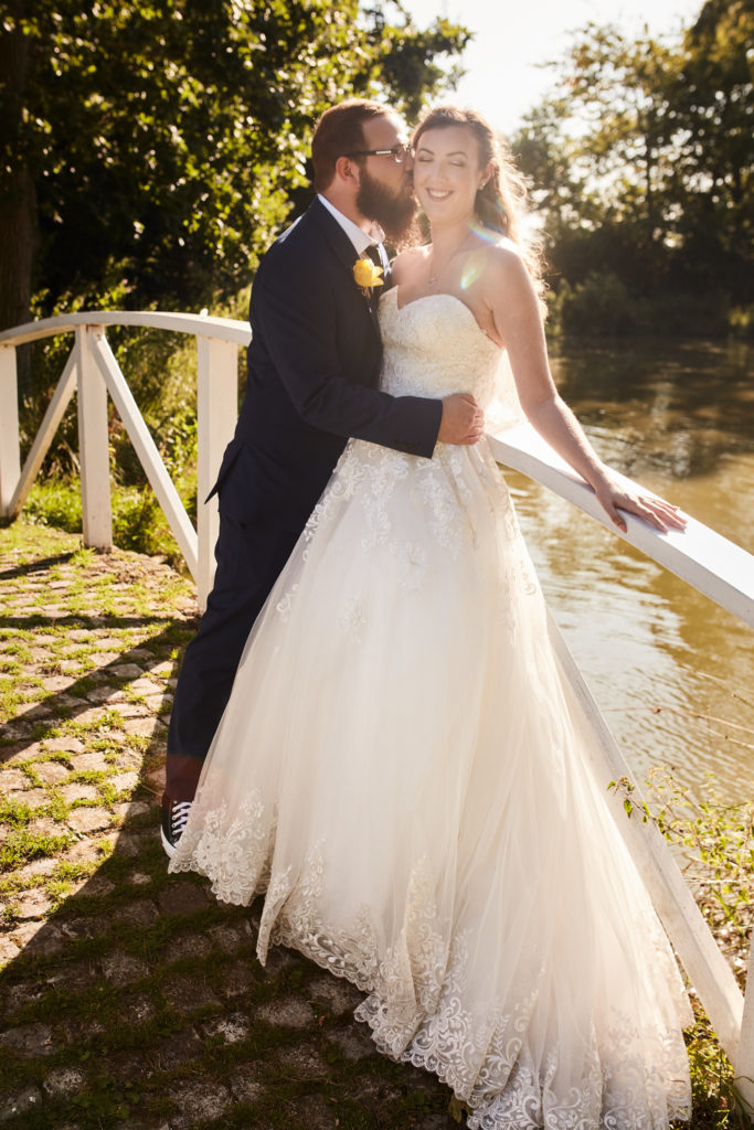 Groom kissing the bride's cheek on the white bridge at Villiers Barn