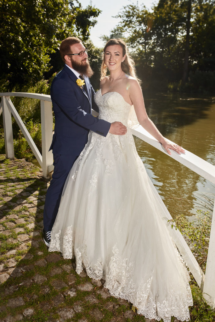 Bride and groom smiling together on the white bridge at Villiers Barn, Essex