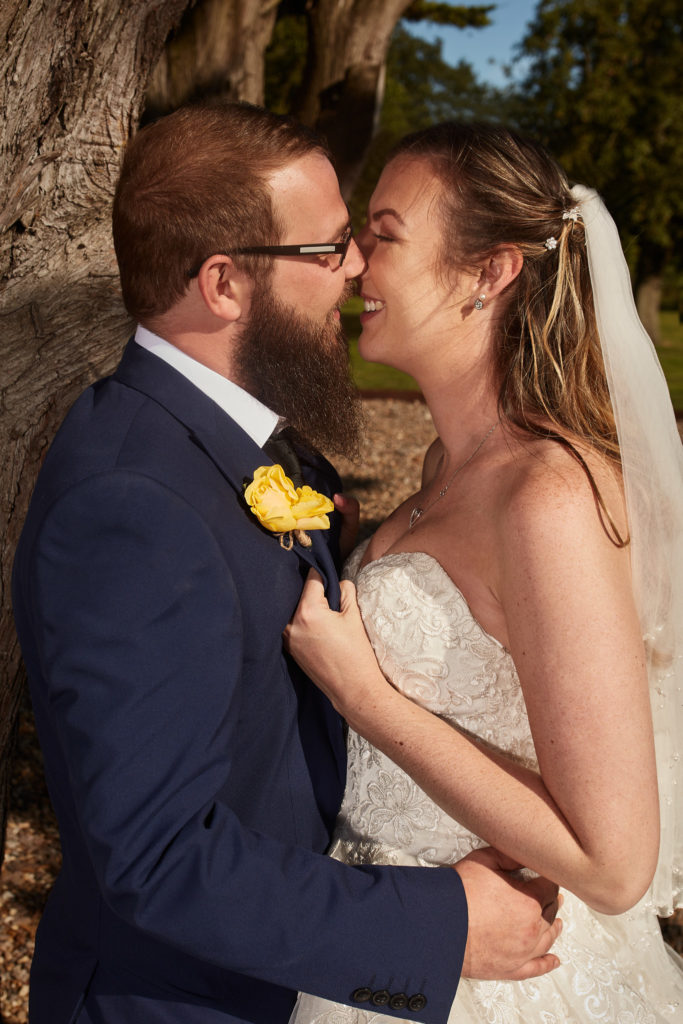 Bride and groom laughing nose to nose under a tree at Villiers Barn