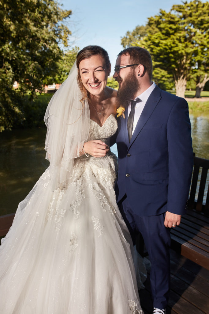 Bride and groom laughing arm in arm on the decking at Villiers Barn