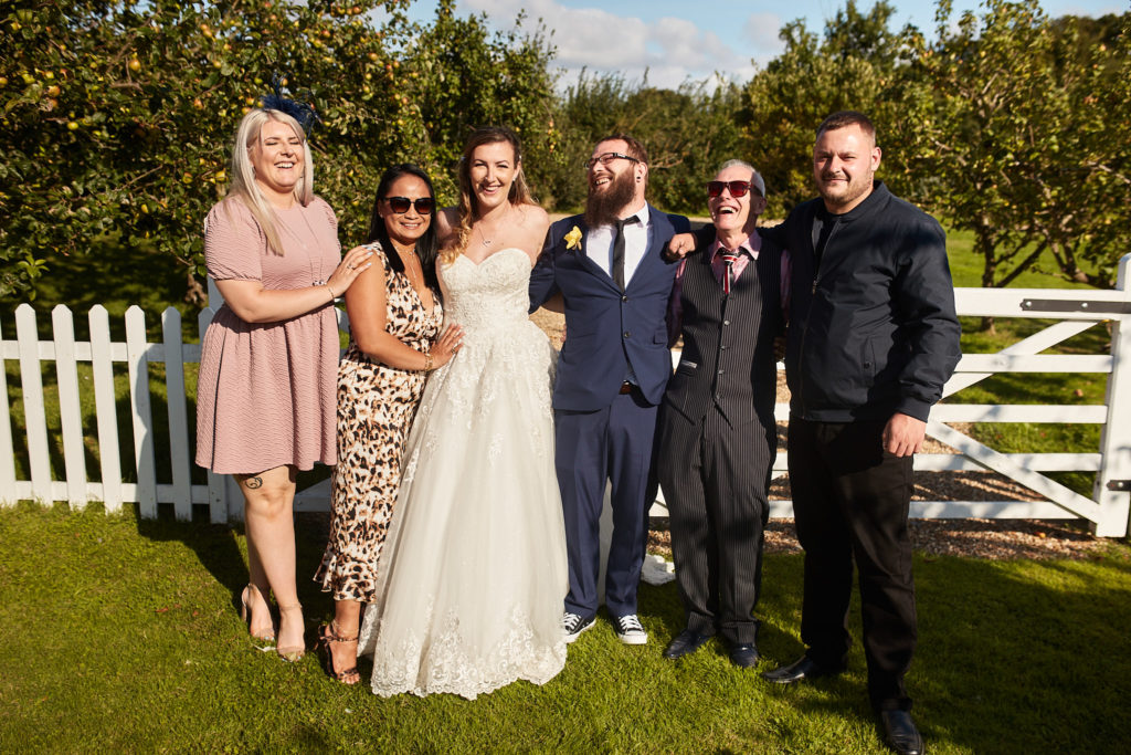 Bride and groom with friends beside a white gate at Villiers Barn