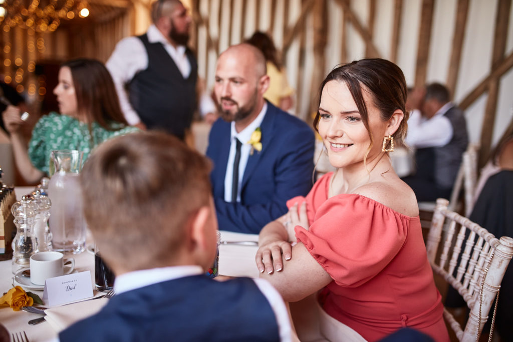 Wedding guests chatting at their table in the oak-beamed barn