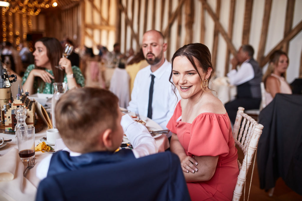 Wedding guest in a coral dress smiling at the table