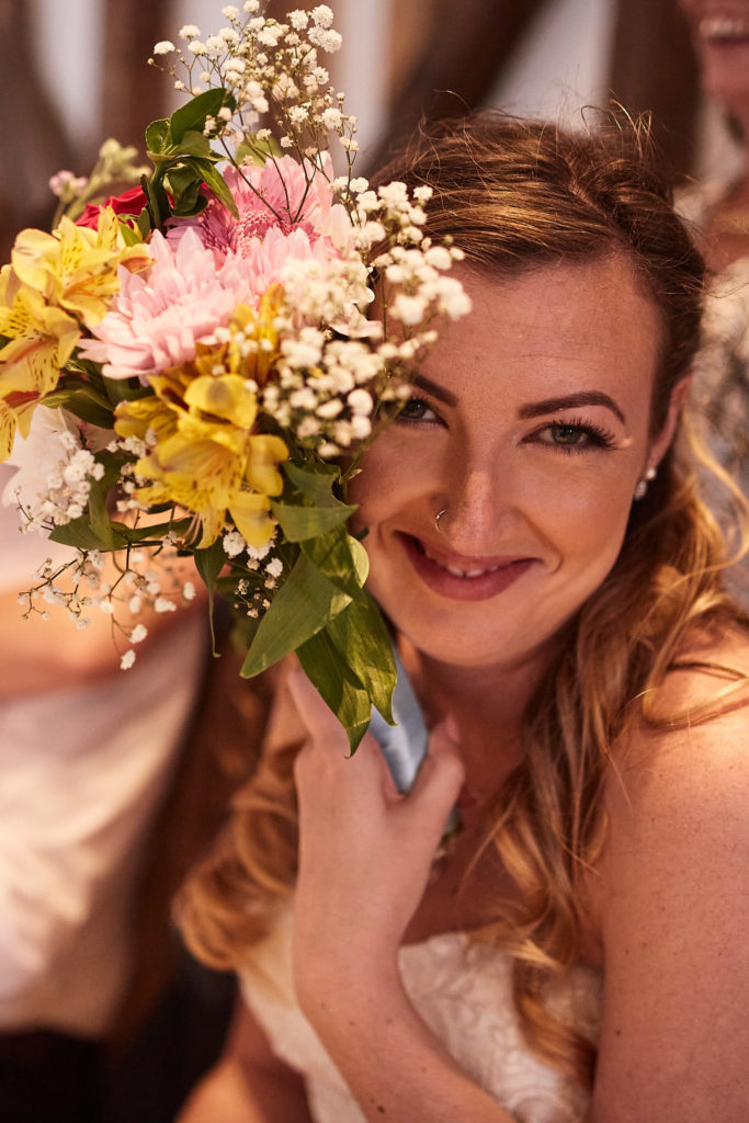 Bride smiling as she holds her bouquet up to her face