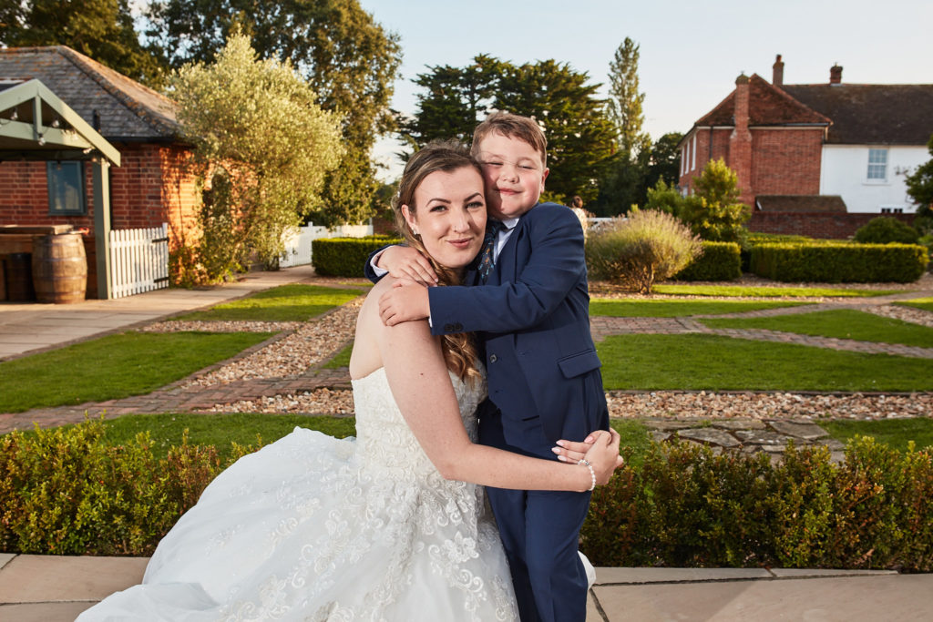 Bride hugging the page boy in the gardens at Villiers Barn