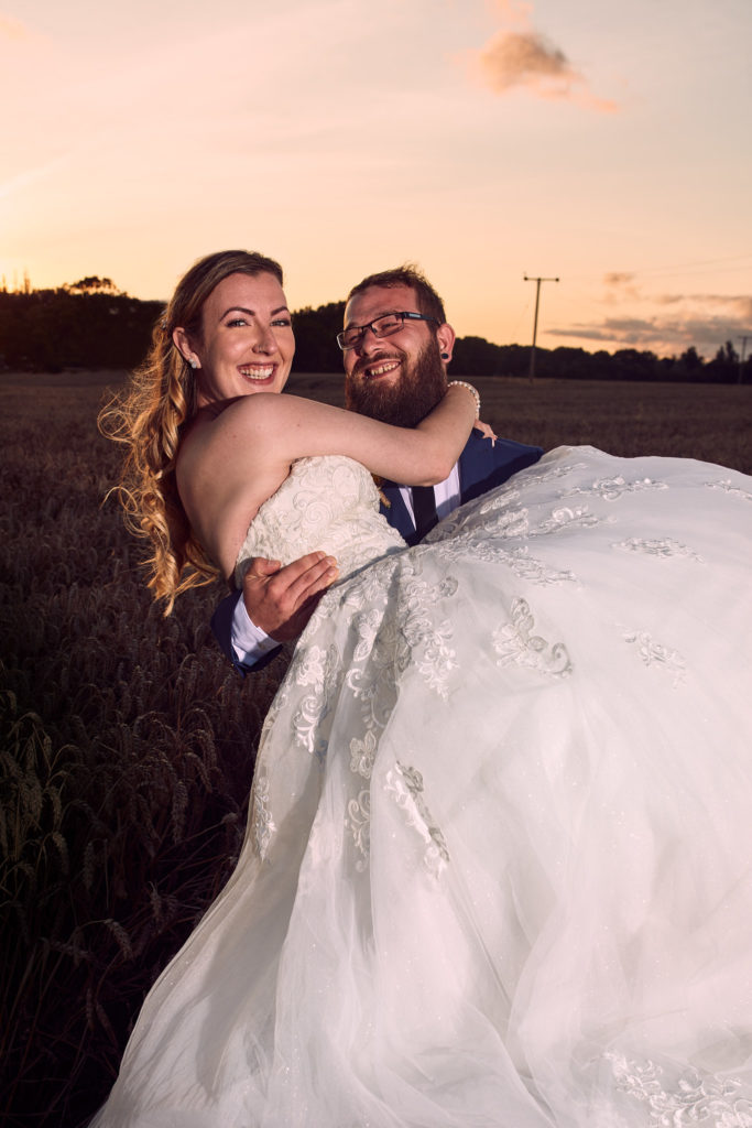 Groom carrying the bride at sunset at Villiers Barn