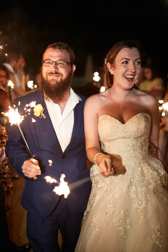 Bride and groom laughing as they hold sparklers at night