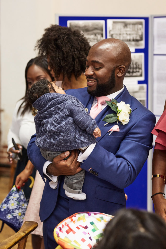 Groom in a blue suit hugging a toddler in church