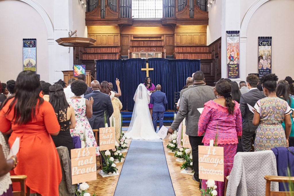 Bride walking down the aisle, seen from behind, as guests stand
