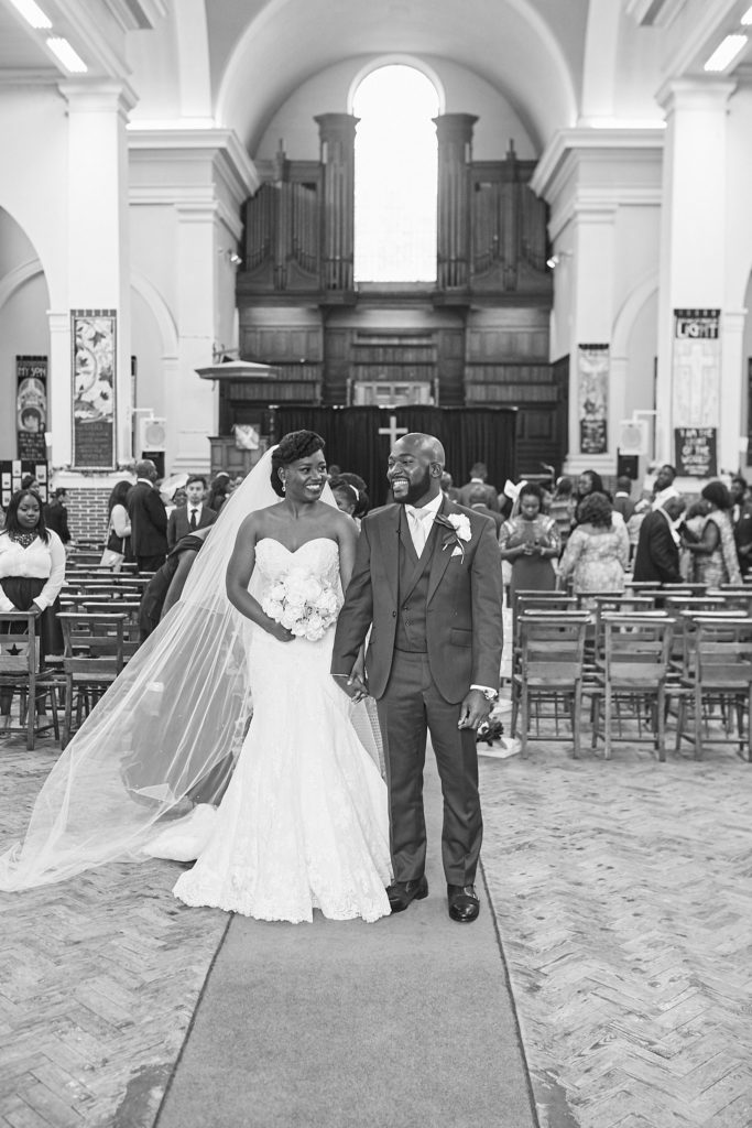 Black and white photo of the bride and groom walking back down the aisle arm in arm