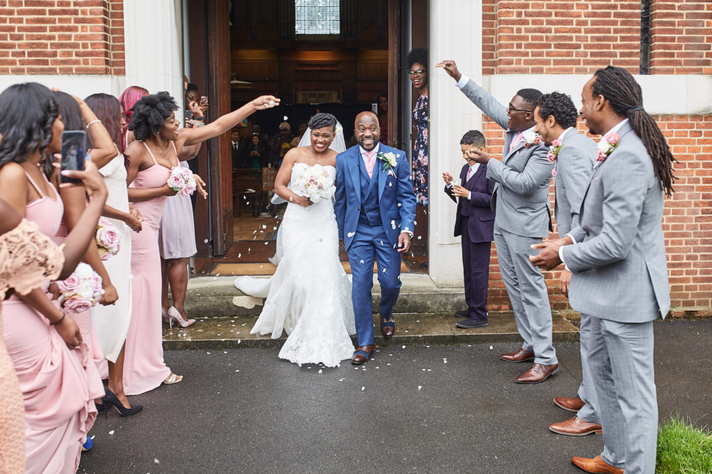 Bride and groom leaving the church as guests throw confetti