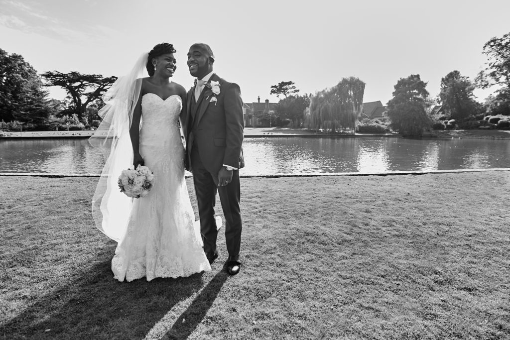 Black and white photo of the bride and groom standing by the lake at Forty Hall