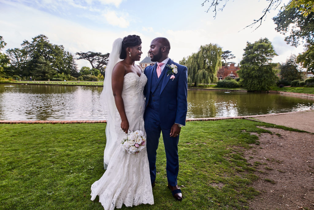 Bride and groom standing together on the lakeside lawn at Forty Hall