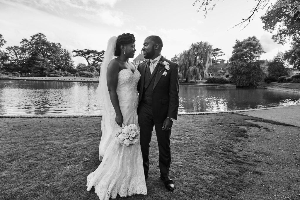 Black and white photo of the bride and groom face to face beside the lake at Forty Hall