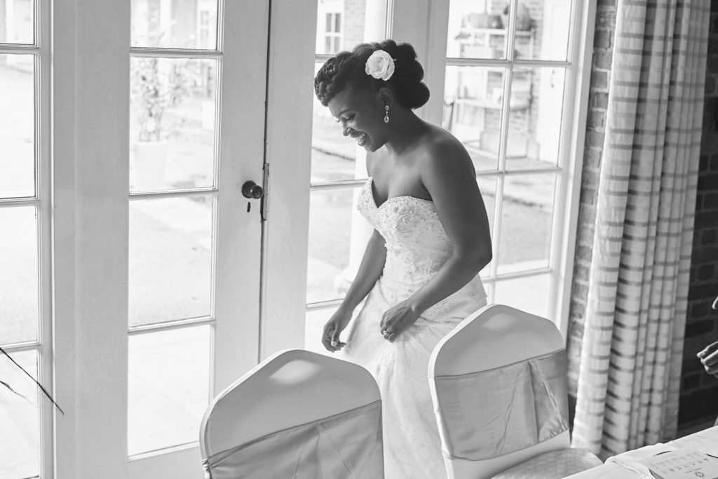 Black and white photo of the bride sitting by a window at the reception