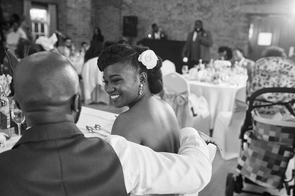 Black and white photo of a guest smiling over her shoulder at the reception