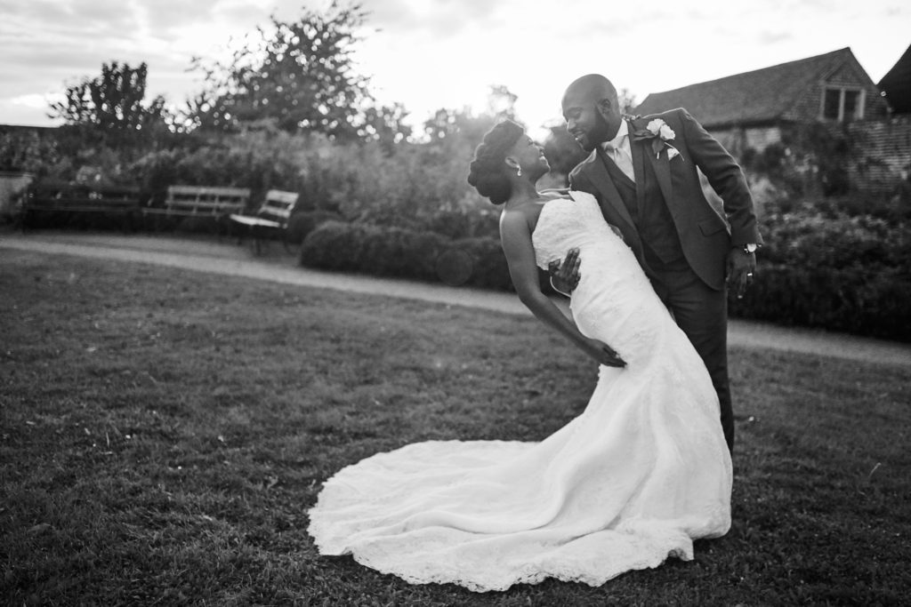 Black and white photo of the groom dipping the bride in the gardens at Forty Hall