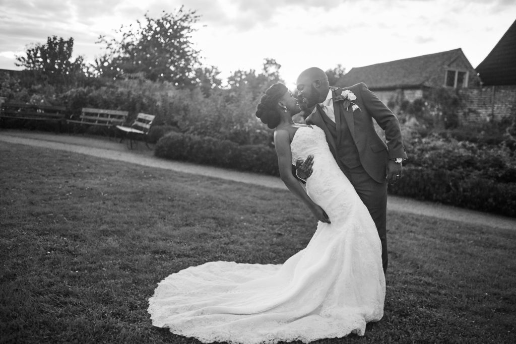 Black and white photo of the groom dipping the bride on the lawn at Forty Hall