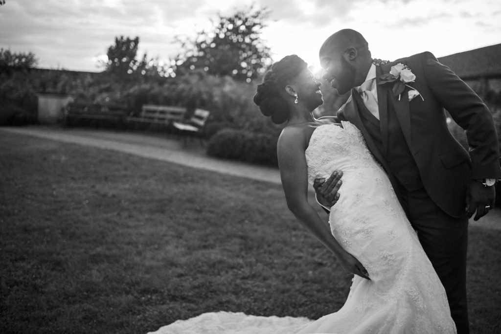 Black and white photo of the bride and groom kissing in the gardens at Forty Hall