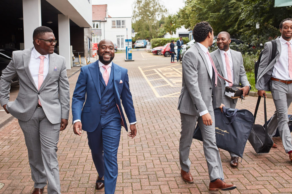 Groom and groomsmen walking to the church in blue and grey suits