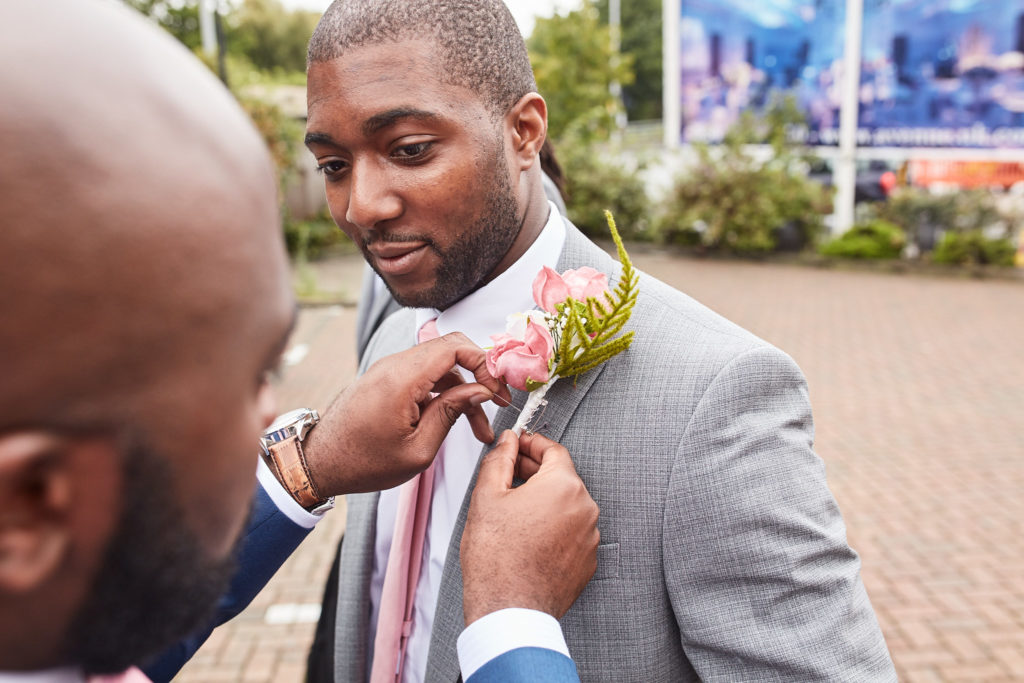 Groomsman having his pink buttonhole pinned on