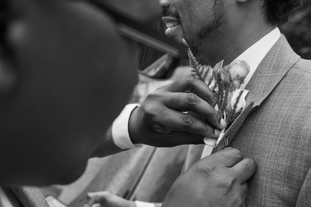 Black and white close-up of a buttonhole being pinned to a jacket
