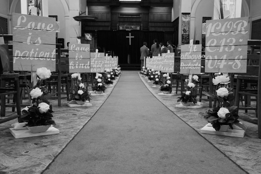Black and white photo of the church aisle lined with flowers and signs