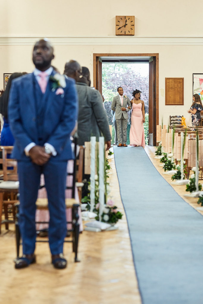 Groom standing at the top of the aisle as the bridal party enters behind him