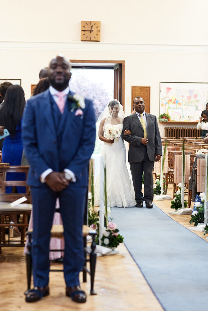Groom waiting as the bride walks up the aisle behind him