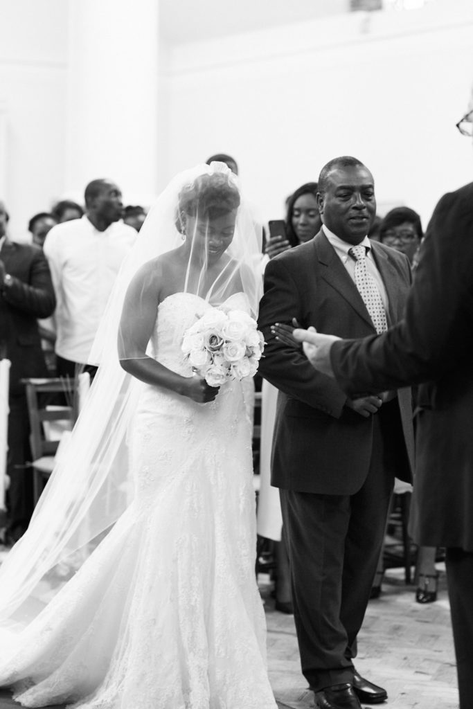 Black and white photo of the bride in her veil on the arm of a man in a suit