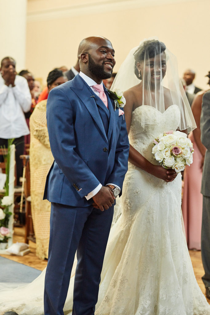Groom smiling beside the bride in her veil during the church service