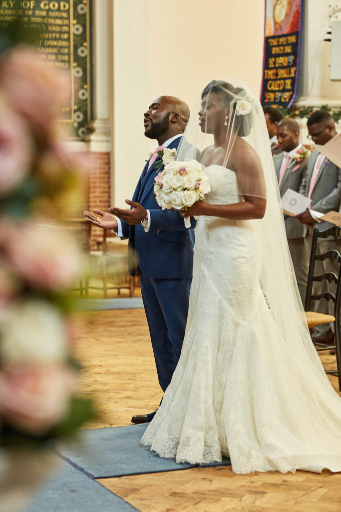Bride and groom facing each other during the ceremony, seen through flowers