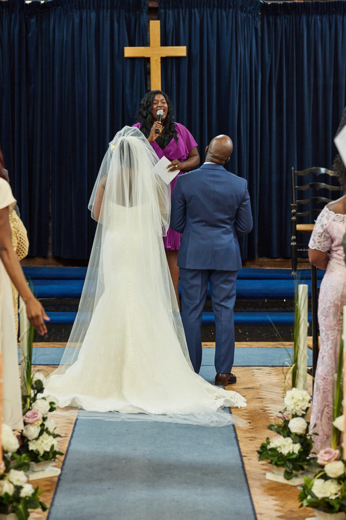Bride and groom standing before the minister beneath a wooden cross