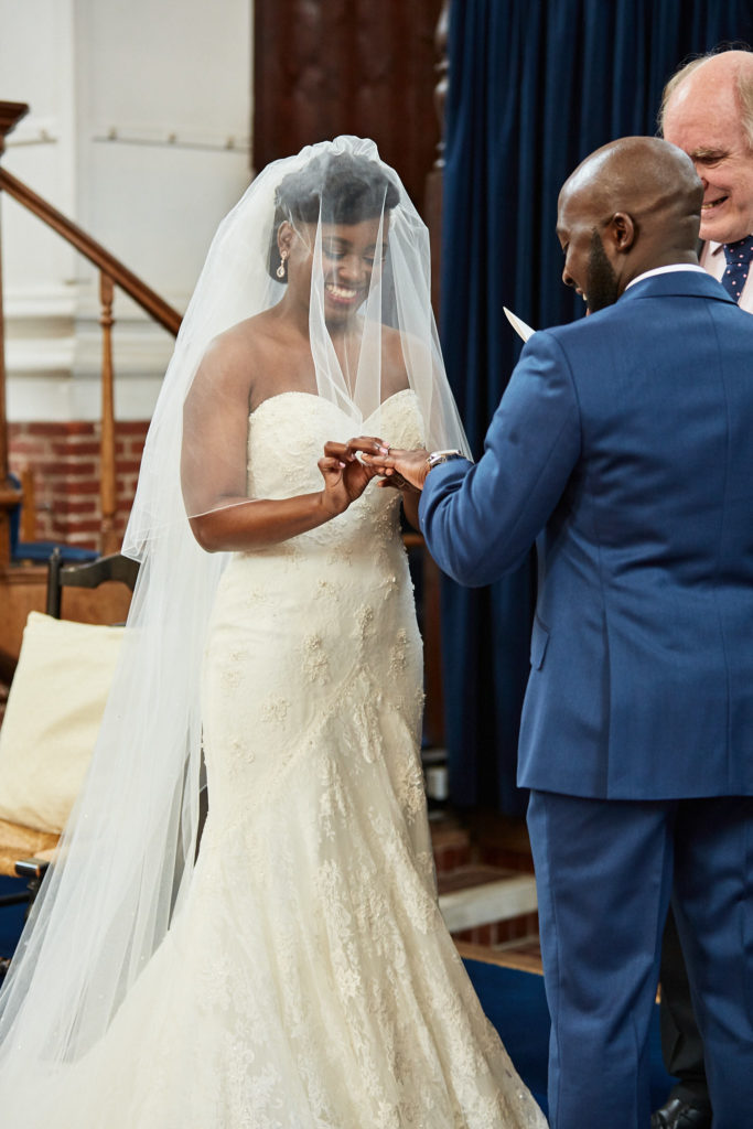 Bride placing the wedding ring on the groom's finger