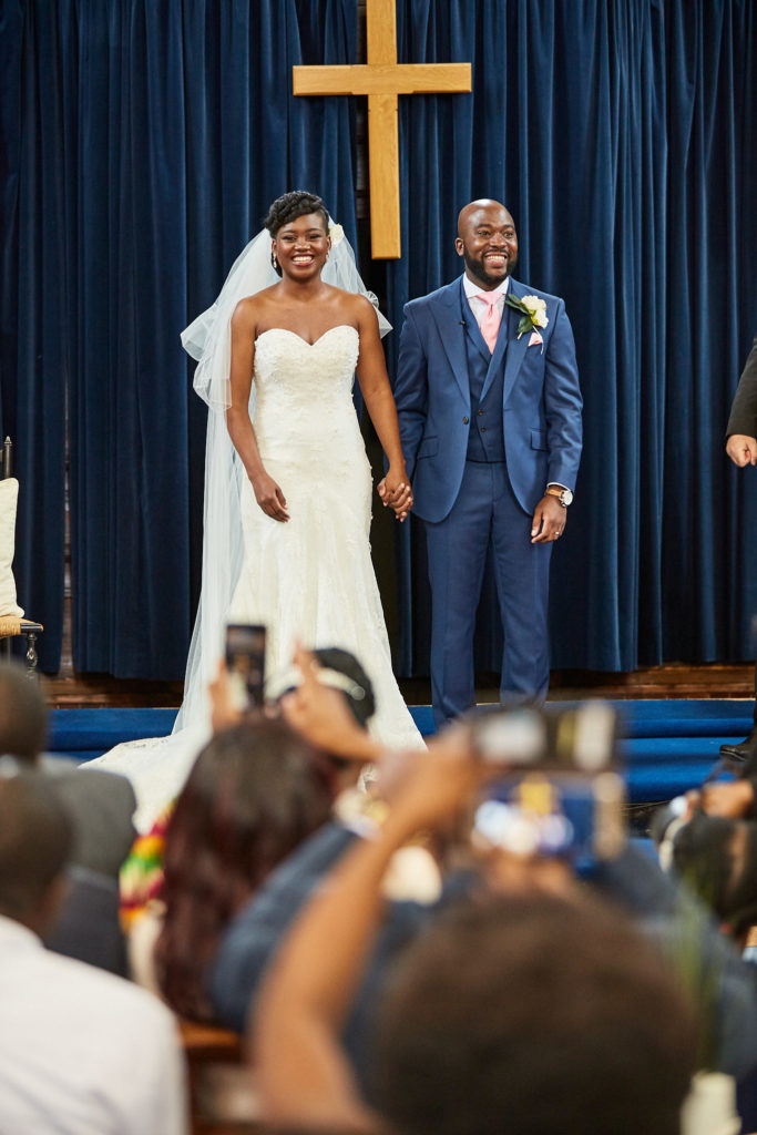 Bride and groom smiling at their guests after the ceremony