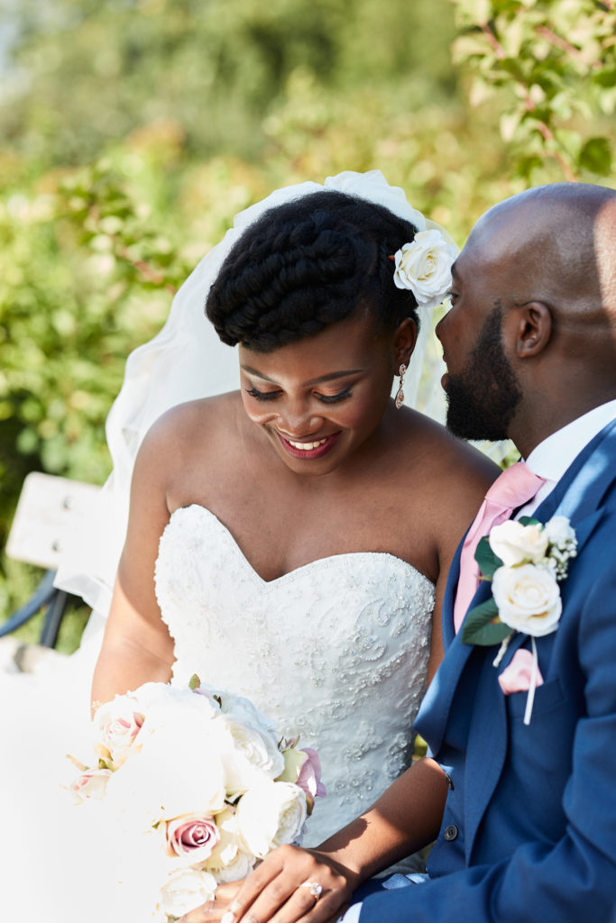Bride looking down at her bouquet as the groom leans towards her