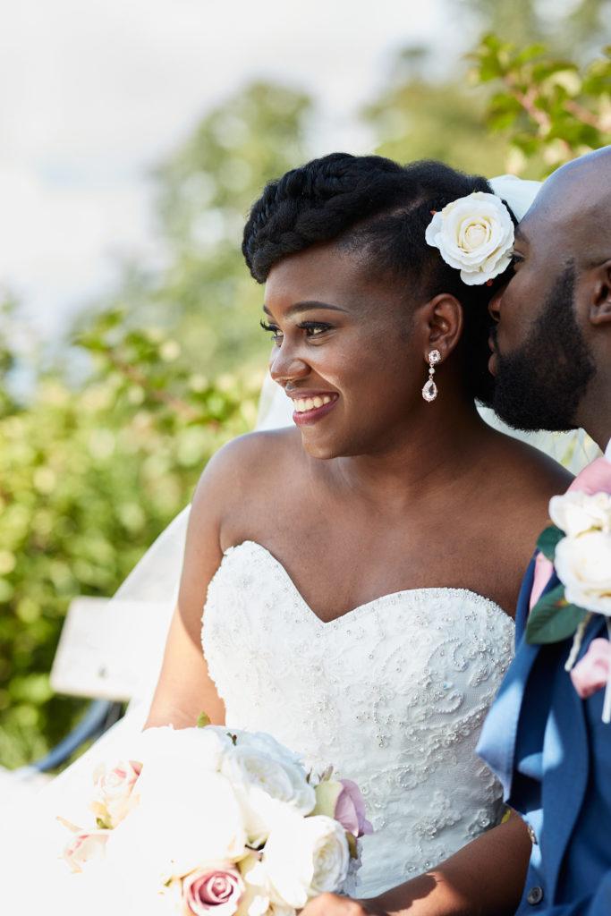 Bride smiling to one side with a white flower in her hair