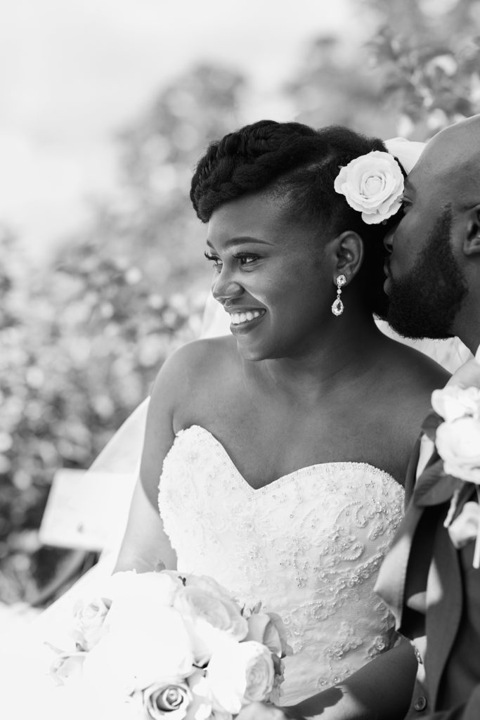Black and white photo of the bride smiling with a flower in her hair