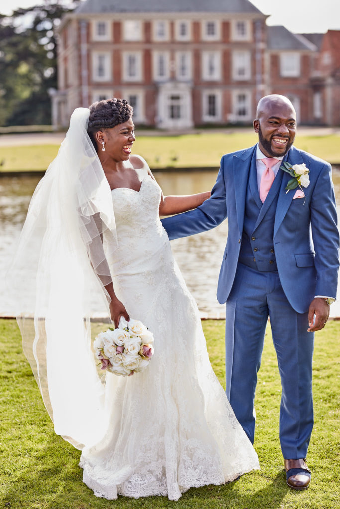 Bride and groom laughing on the lawn in front of Forty Hall