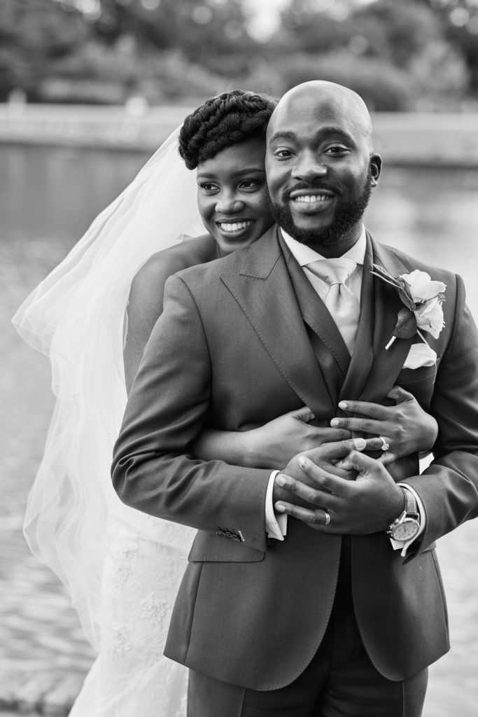 Black and white photo of the bride hugging the groom from behind at Forty Hall