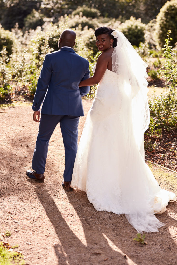 Bride looking back over her shoulder as she walks with the groom at Forty Hall
