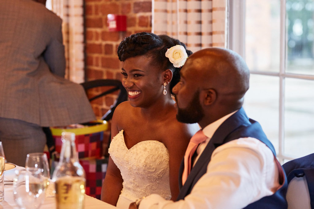 Bride laughing as the groom whispers to her at the top table