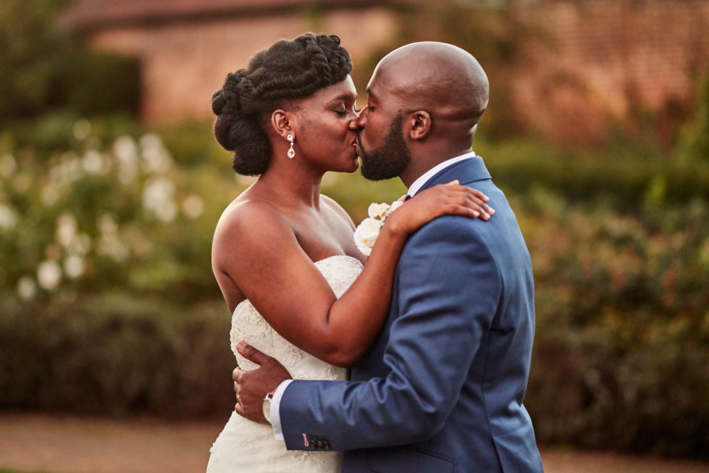 Bride and groom kissing in the gardens at Forty Hall at dusk