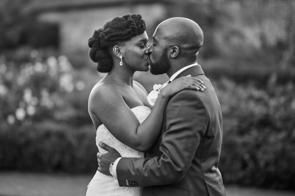 Black and white photo of the bride and groom kissing in the gardens at Forty Hall
