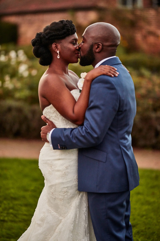 Bride and groom kissing in the garden at Forty Hall in the evening