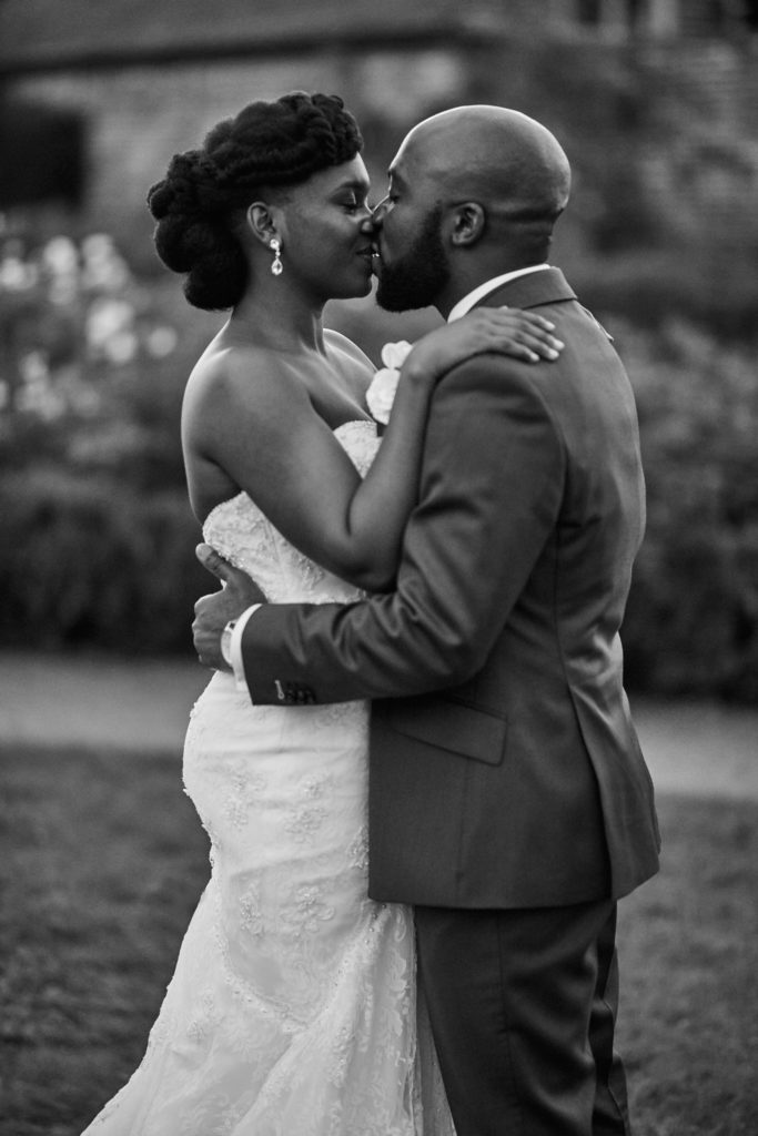 Black and white photo of the bride and groom kissing with her arms round his neck at Forty Hall