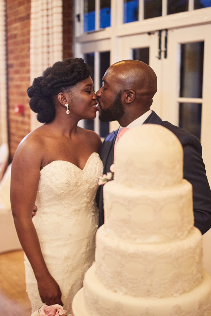 Bride and groom kissing beside their wedding cake