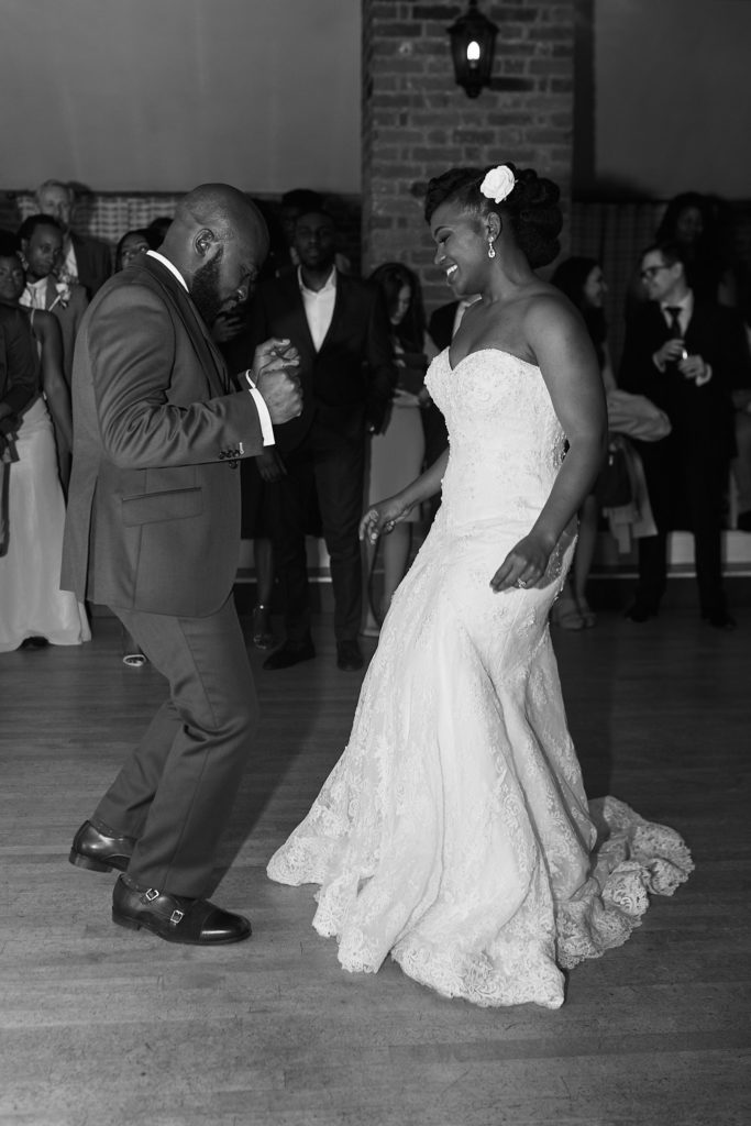 Black and white photo of the bride and groom dancing as guests watch