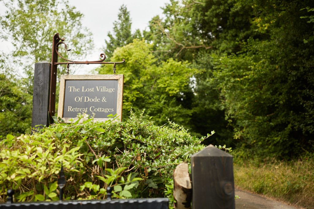 Sign at the entrance to the Lost Village of Dode among the trees