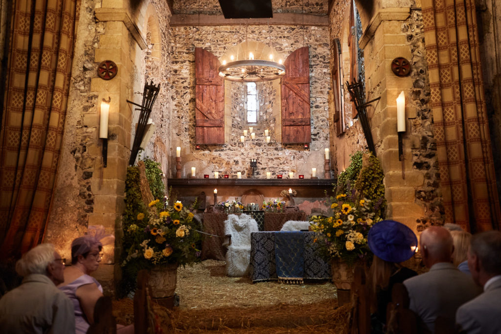 Wide view of the candlelit wedding ceremony inside the Norman church at Dode
